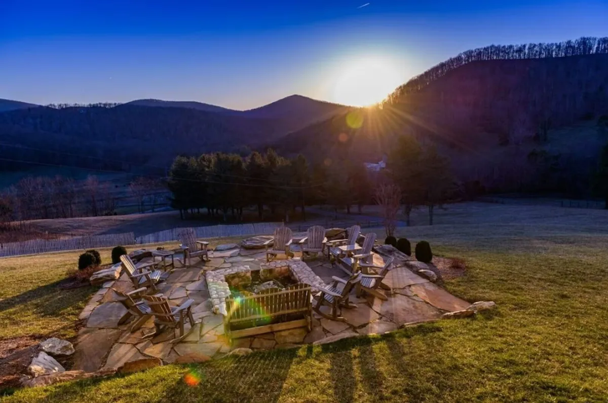 This image features a cozy fire pit surrounded by Adirondack chairs, set against a stunning mountain backdrop. The setting inspires thoughts of gathering under the stars after a day of adventure, with ample space for group relaxation and storytelling.