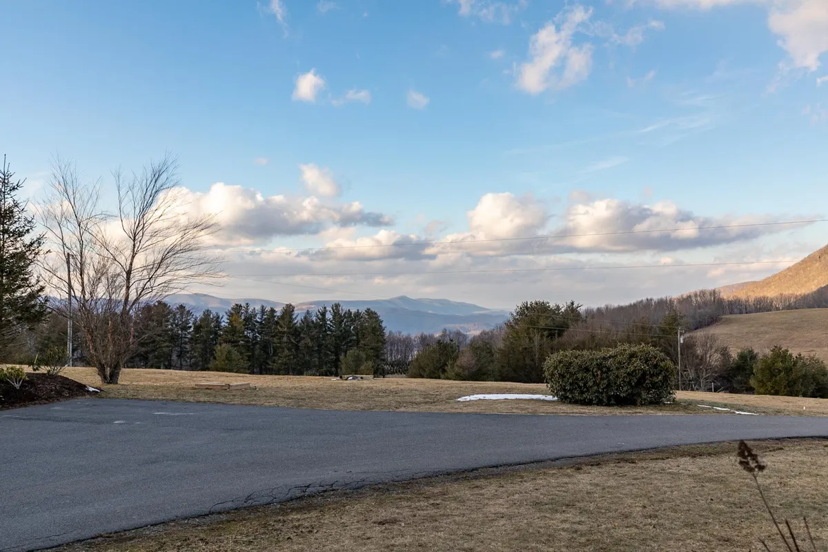 A dramatic view of an open field, trees, and a distant mountain range under a vast sky, evoking the region’s natural beauty and potential for hiking, picnicking, and exploration.