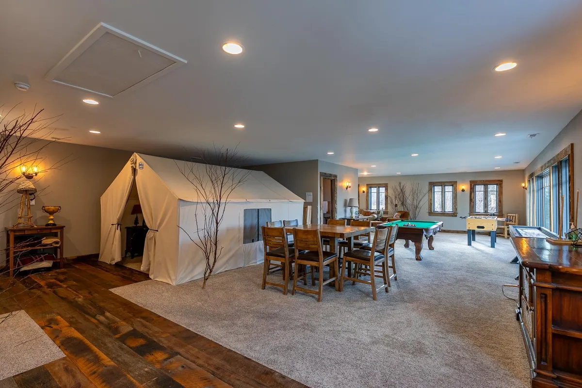 An interior space featuring a unique tent structure, a large dining table, and a pool table—blending the adventure of glamping with the comforts of indoor amenities. The setting is informal, playful, and conducive to group activities like game nights and shared meals.